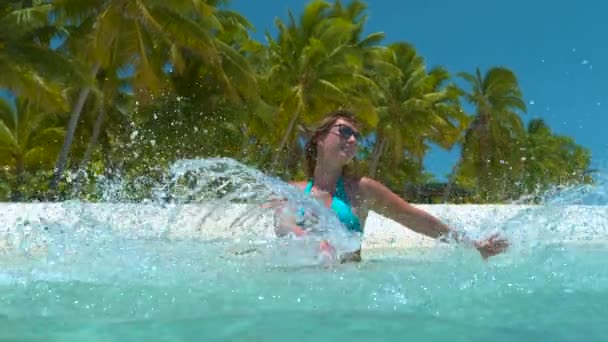 CLOSE UP: Smiling woman on vacation splashing the crystal clear ocean water. — Stock Video