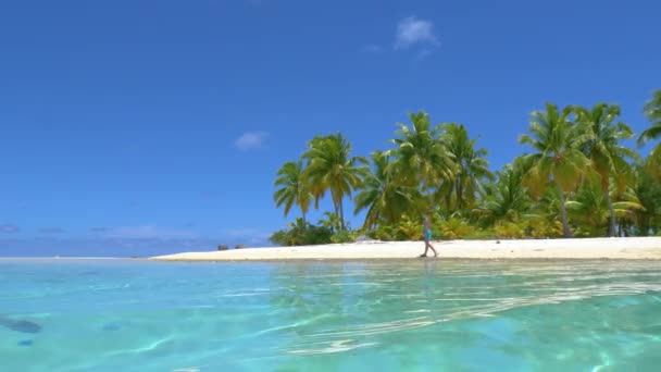 FAIBLE ANGLE : Fille caucasienne sur une promenade pittoresque le long d'un rivage sablonneux tropical luxuriant