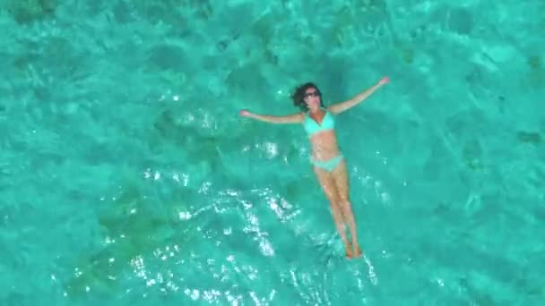 Volando sobre una mujer despreocupada flotando sobre su espalda en medio del océano. — Vídeos de Stock
