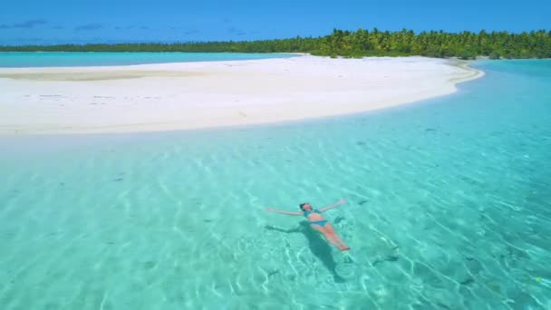 AERIAL: Flyger nära ung kvinna simmar på ryggen nära sandstrand. — Stockvideo