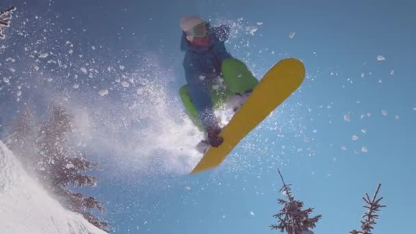 Pomalý pohyb zavřít: vzrušený snowboardista skáče přes slunce v horské krajině — Stock video