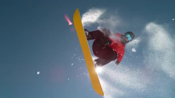 MOVIMIENTO Lento CERRAR: snowboarder saltar y volar sobre el sol en el cielo azul claro — Vídeo de stock