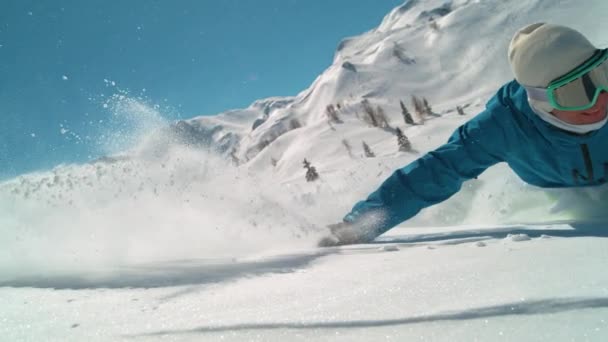 CLOSE UP: Smiling man snowboarding off piste drags his hand through the snow. — 비디오