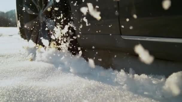 SLOW MOTION: Car driving off road on sunny day spitting up pieces of wet snow. — Stock Video