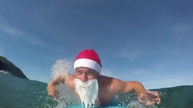 Slow Motion Close: Neşeli Uoung Noel Baba Okyanusta eğlenceli dalgalarda sörf yapıyor