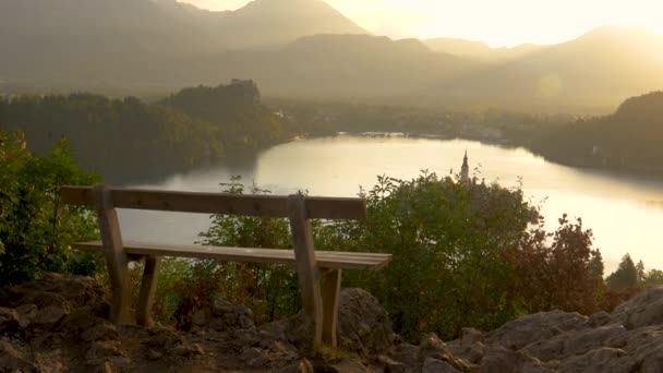 Κοντινό πλάνο: Γραφικό πλάνο ενός άδειου ξύλινου πάγκου και της γνωστής λίμνης Bled. — Αρχείο Βίντεο