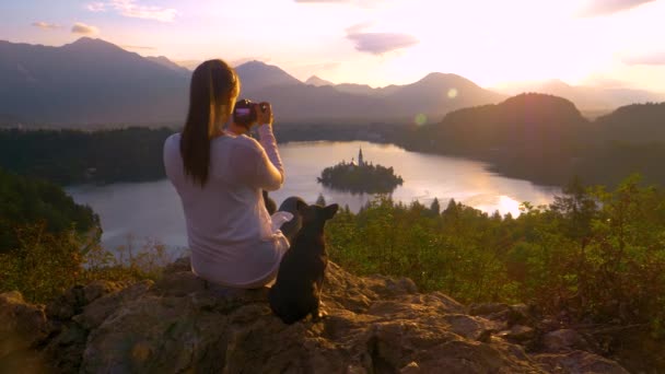 Slow Motion: Kadın fotoğrafçı gündoğumunda Bled Gölü 'nde kilisenin fotoğraflarını çekiyor — Stok video