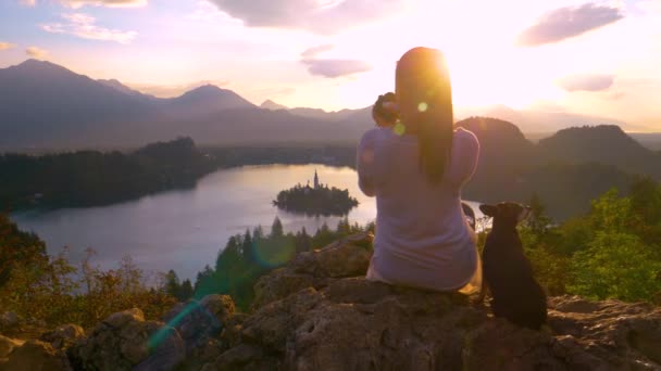 LENS FLARE CLOSE UP: Unrecognizable woman photographing lake Bled at sunset. — 비디오