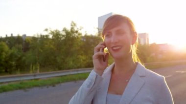 Kaldırımda yürürken telefonuyla konuşan şık bir iş kadını.