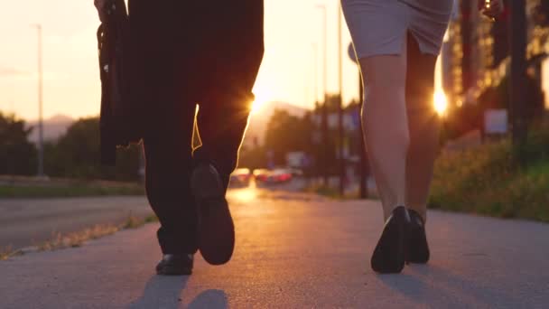 LENS FLARE Girl in high heels and her co-worker walk down the sidewalk at sunset — Stock Video