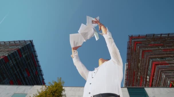スローモーション:幸せな若い男は昇進した後、空気中に紙を投げます. — ストック動画