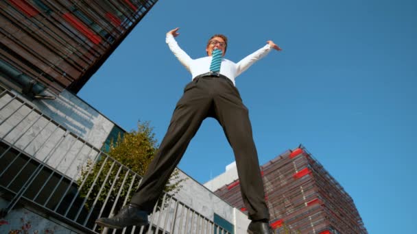 低角度:陽気なビジネスマンは仕事の後彼の腕をジャンプし、拡張します。. — ストック動画