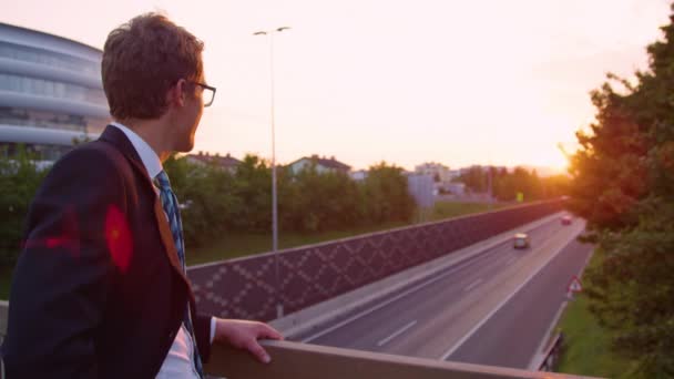 Movimiento lento: Yuppie alegre mirando a la cámara y mira a la puesta de sol . — Vídeos de Stock