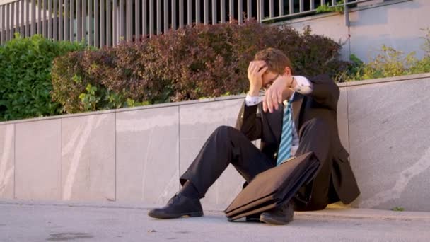 SLOW MOTION: Man sits on the pavement and strikes briefcase after getting fired. — Stockvideo