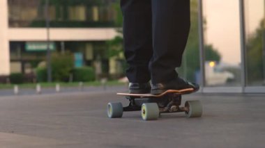 CLOSE UP: Unrecognizable yuppie going home from work on his electric skateboard