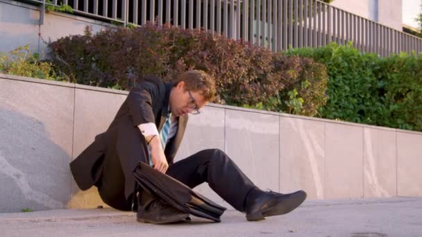CLOSE UP: Desperate businessman picks up his briefcase and walks down sidewalk. — Stockvideo