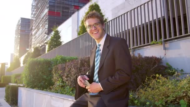 SLOW MOTION, PORTRAIT: Cheerful young businessman smiles and waves his money. — Stockvideo