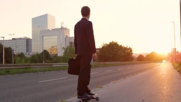 LENS FLARE: Aktywny biznesmen płynący ulicą słoneczną na longboardzie. — Wideo stockowe
