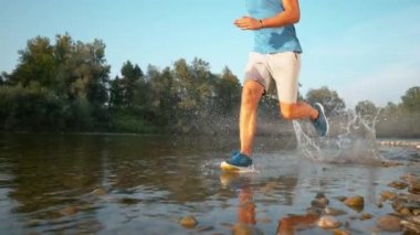 TIME WARP: Cinematic shot of young man running along the river on sunny morning.