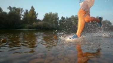 SLOW MOTION EFFECT: Cool shot of sportsman going for a jog on the riverbank.