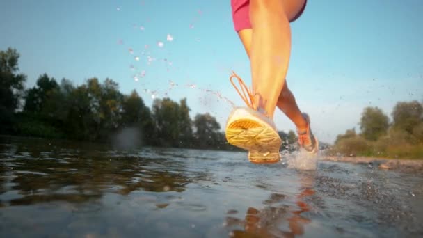 CERRAR: Ajuste mujer joven corriendo en el refrescante río en una tarde soleada . — Vídeos de Stock