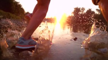 SLOW MOTION: Golden sunbeams shine on fit couple jogging in the tranquil stream.