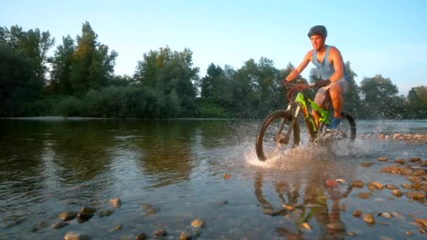 Movimiento lento: deportista feliz montar su bicicleta a través de las aguas poco profundas vidriosas . — Vídeos de Stock