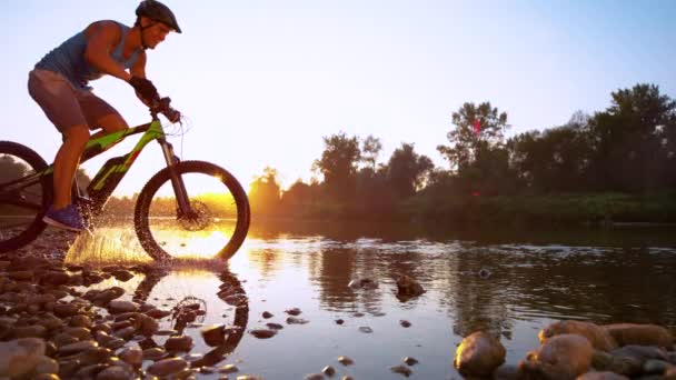 Zeitlupensportler radelt am idyllischen Morgen durch flachen Bach — Stockvideo