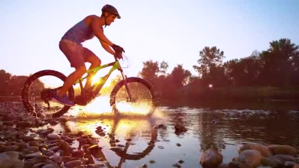 Time Remap: Coole Aufnahme eines Mountainbikers, der an einem goldenen Morgen über einen Fluss fährt. — Stockvideo