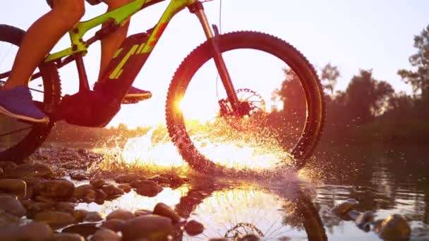 LENS FLARE: Unrecognizable cross country cyclist splashes the river water. — Stock Video