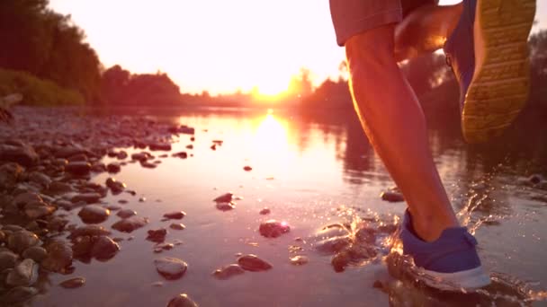 Медленное приближение Неузнаваемый спортсмен бегает по мелкой реке на закате — стоковое видео