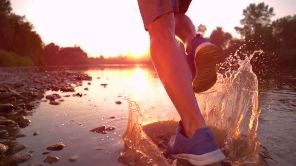 SUPER SLOW MOTION: Athletic man runs in the shallow stream towards the sunset. — 비디오