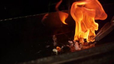 Slow Motion, Macro, Dof: geleneksel bıçakların dövüldüğü demircinin kızgın yağdan çıkardığı yanan bir bıçağın sinematik çekimi. Bıçak ağzı soğurken yağ yüzeyinden duman çıkıyor.
