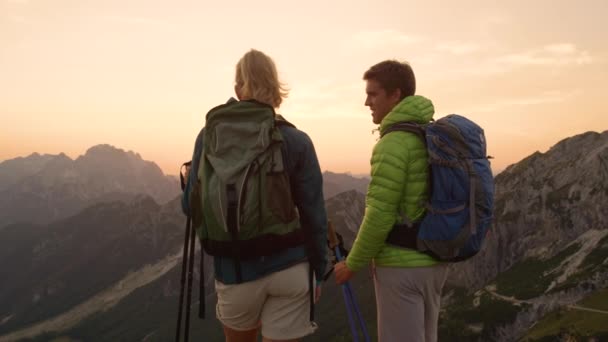 FLARE DE LA LENTE: Pareja joven que camina en las impresionantes montañas cinco en la puesta del sol . — Vídeos de Stock