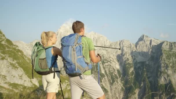 LEZÁRÁS: Férfi és női túrázók a hegyekre mutogatnak a botjaikkal. — Stock videók
