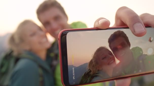 Macro, Dof: Ευτυχισμένο ζευγάρι πεζοπόρων παίρνει μια selfie υψηλή στις Άλπεις κατά την ανατολή του ηλίου. — Αρχείο Βίντεο