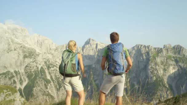 UKONČENÍ: Nerozpoznatelný pár turistů roztáhnout paže po dosažení vrcholu hory — Stock video