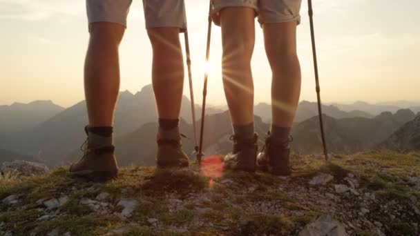 FECHAR UP: Mulher ativa e homem ficar no pico da montanha e assistir ao nascer do sol. — Vídeo de Stock