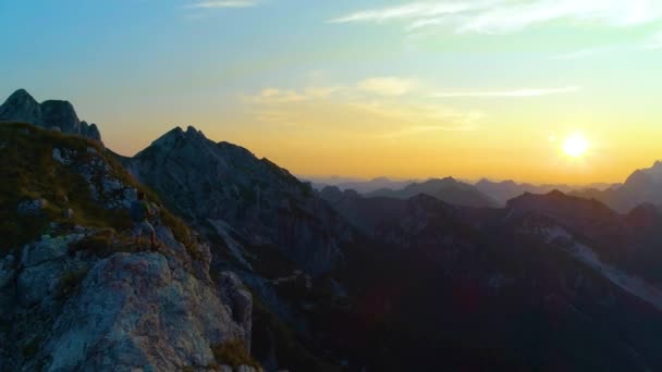 Volando alrededor de un excursionista masculino de pie en la cima de la montaña al atardecer . — Vídeos de Stock