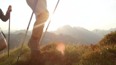 Yakından: Tanımlanamayan yürüyüşçüler deri botlar giyerek çimenli bir tepede yürüyorlar.