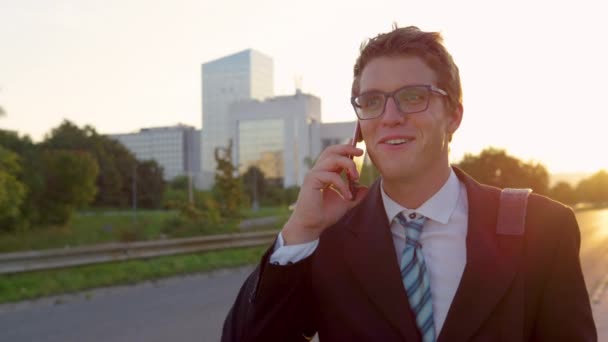 LENS FLARE Golden sunbeams shine on yuppie talking on the phone while going home — Stock Video