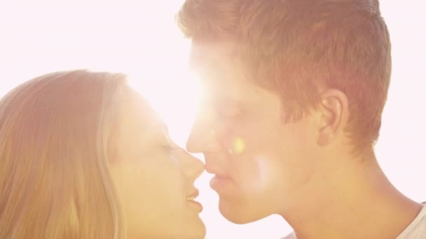 LENS FLARE: Handsome man gently kisses his cheerful girlfriend on the nose. — Stock Video