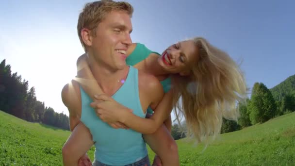 Portrét: Veselý muž dává jeho blond vlasy přítelkyně zábavné prasátko jízda. — Stock video