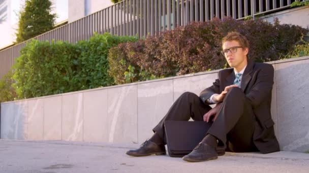 LENS FLARE: Businessman sitting on the street and shaking his head in disbelief. — Stock Video