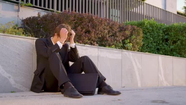 Αργή κίνηση: λυπημένος άνθρωπος κάθεται στο πεζοδρόμιο και θάβει το κεφάλι του στα χέρια του. — Αρχείο Βίντεο