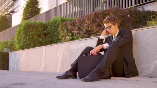 SUN FLARE: Businessman sits on the pavement and shakes his head after losing job — Stock Video