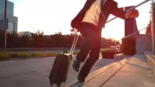 MOCIÓN LENTA: Joven hombre de negocios corriendo por una escalera con su maleta . — Vídeos de Stock