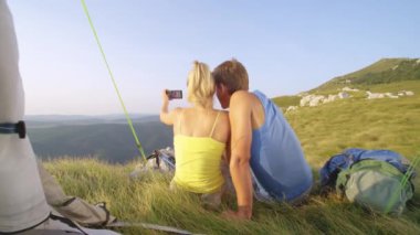 Yakından: Genç bir adam ve kadın yürüyüş macerası sırasında fotoğraf çekiyorlar.