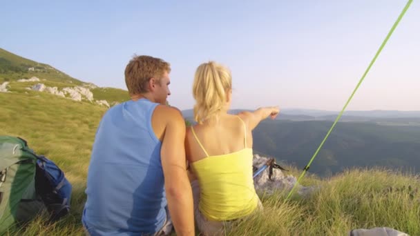 MOCIÓN LENTA: Hiker girl señalando y mostrando a su novio feliz el paisaje . — Vídeos de Stock