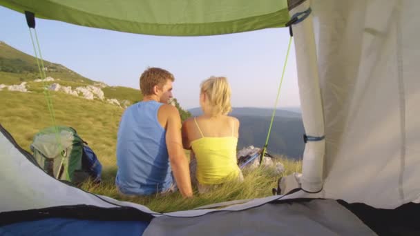 Nah dran: Unbekümmertes Touristenpaar küsst sich beim Sitzen vor Zelt. — Stockvideo